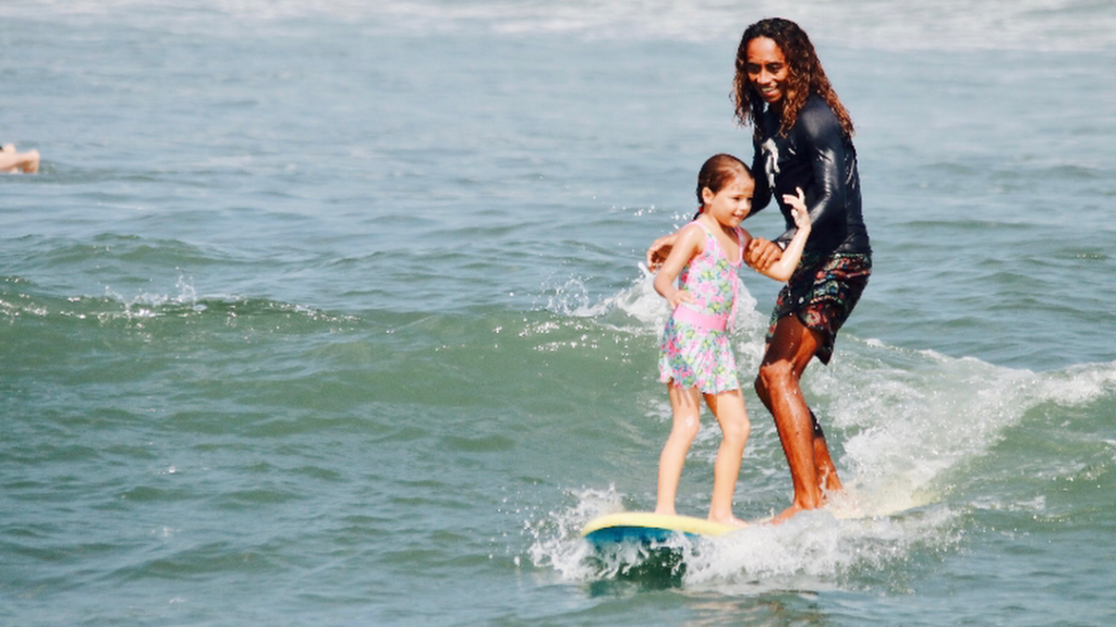 Surf instructor teaching a child to surf at Kedungu Beach near Tanah Lot